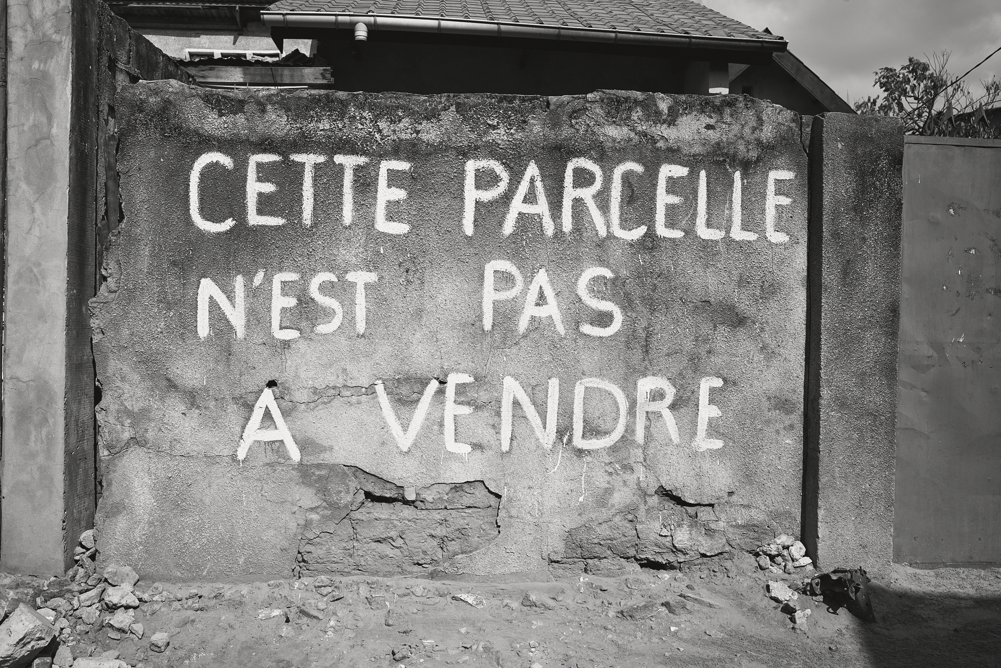 Schriftzug „Cette parcelle n'est pas à vendre“ auf einer Mauer.