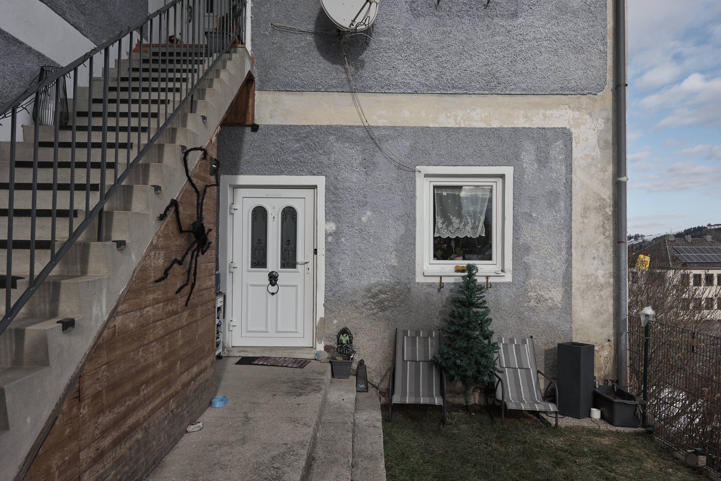 Blick auf den Hauseingang einer Kellerwohnung mit Treppenaufgang und kleinem Garten.